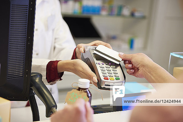 Customer paying cashless with credit card in a pharmacy