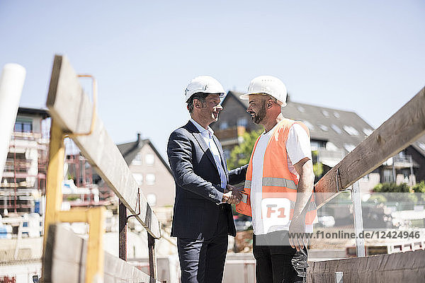 Man in suit shaking hands with construction worker on construction site