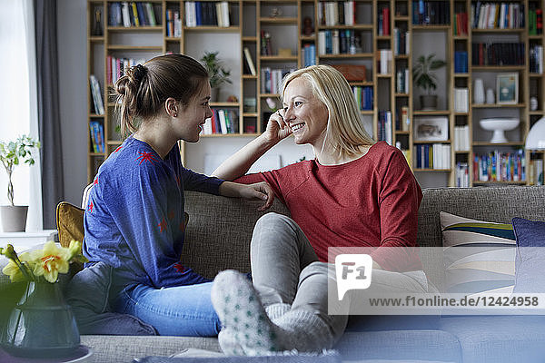 Mother and adolescent daughter talking  sitting on couch