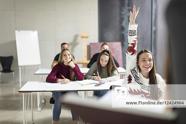 Smiling teenage girl raising hand in class