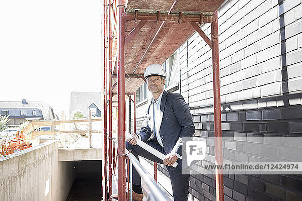 Architect wearing hard hat standing on scaffolding on construction site