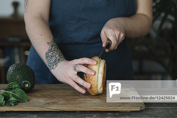 Woman preparing vegan burger  cutting bread roll