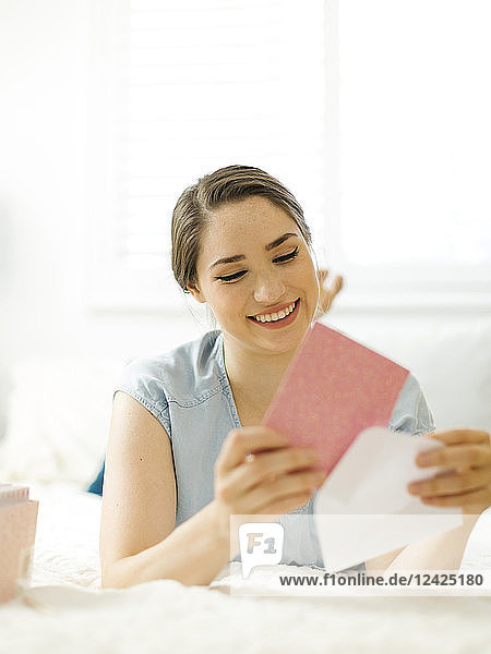 Frau steckt Karte in Umschlag auf Bett