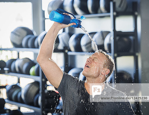 Man pouring water on himself in gym