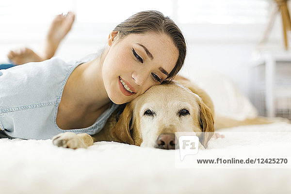 Frau auf dem Bett liegend mit Hund