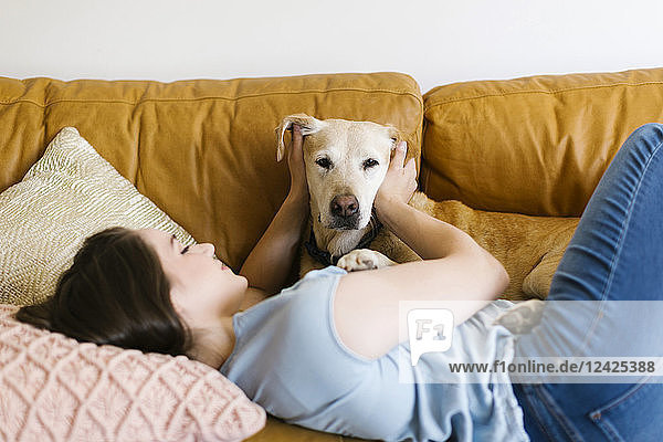 Woman lying on sofa with dog