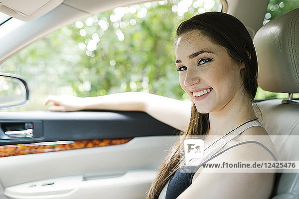 Smiling young woman sitting in car