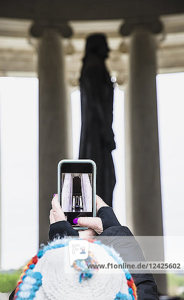 Frau fotografiert Statue mit Smartphone