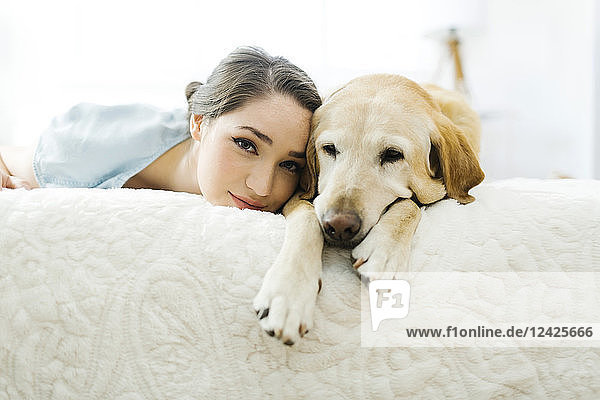Frau auf dem Bett liegend mit Hund