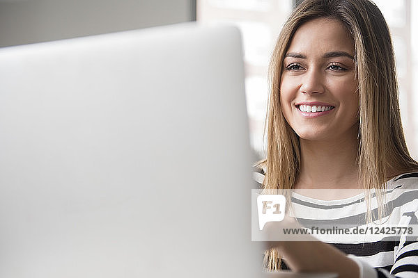 Lächelnde junge Frau am Laptop