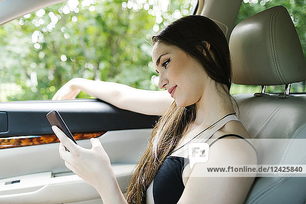 Young woman using smart phone in car