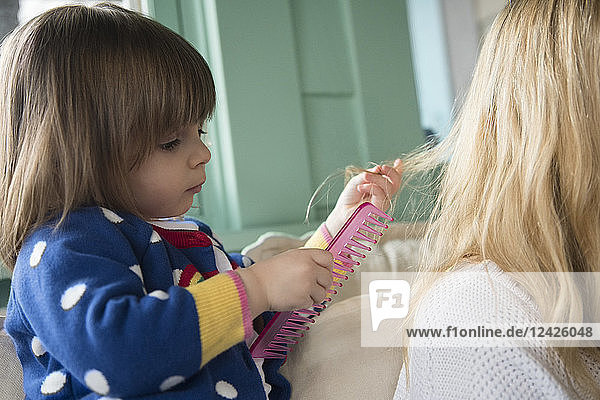 Kleines Mädchen (2-3) kämmt die Haare der Mutter