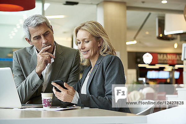 Geschäftsleute benutzen ihr Smartphone in der Cafeteria