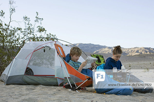 Boy and teenage girl camping in desert with boy looking at map  Death Valley National Park  California  USA