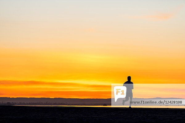 Silhouette einer Person  die bei Sonnenaufgang joggt