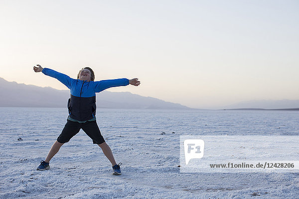 Young boy standing with spread arms on salt pan  Death Valley National Park  California  USA