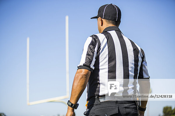 Rear view of football referee wearing black and white striped shirt