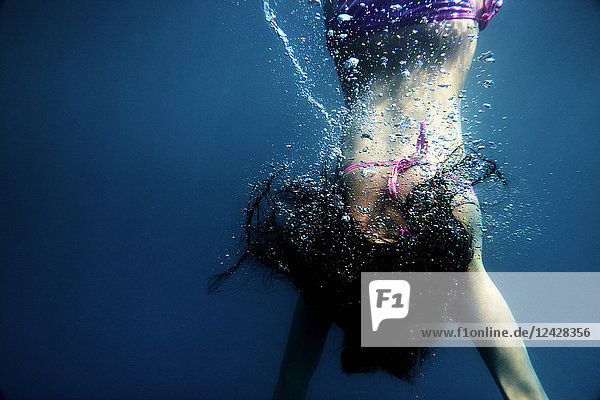 Unterwasseransicht einer Frau im Bikini beim Schwimmen