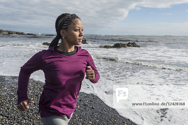 Taillenaufnahme einer einzelnen Frau  die am felsigen Strand läuft  Kittery  Maine  USA