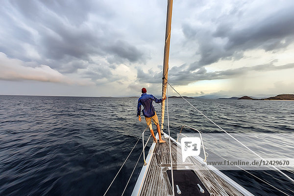 Rear view shot of single man standing on bow of yacht  Lombok  Indonesia