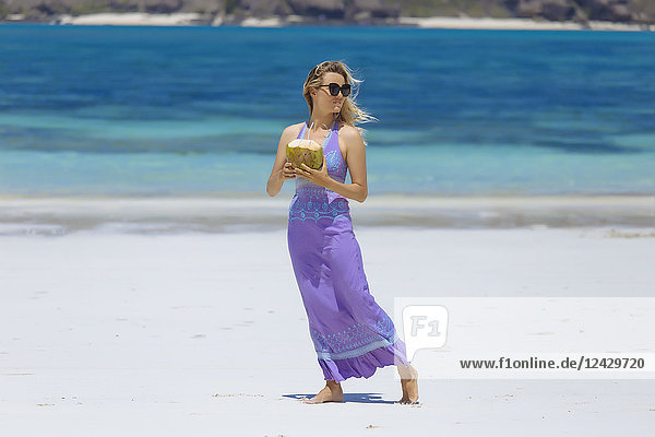 Front view shot of woman in purple dress with coconut drink on beach  Kuta  Lombok  Indonesia