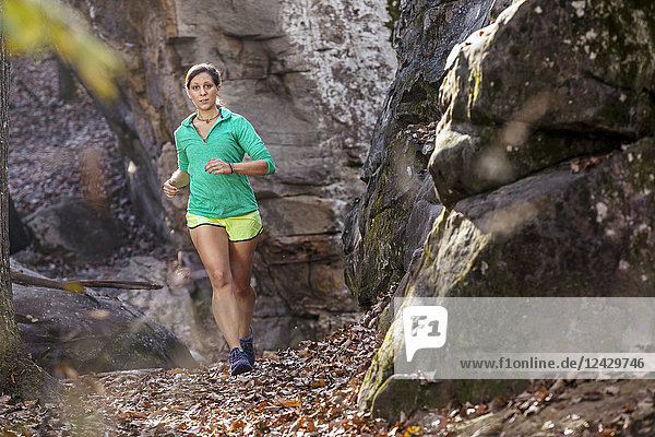 Vorderansicht einer Frau  die in natürlicher Umgebung an Felsformationen im Moss Rock Preserve in Hoover  Alabama  USA  entlang läuft
