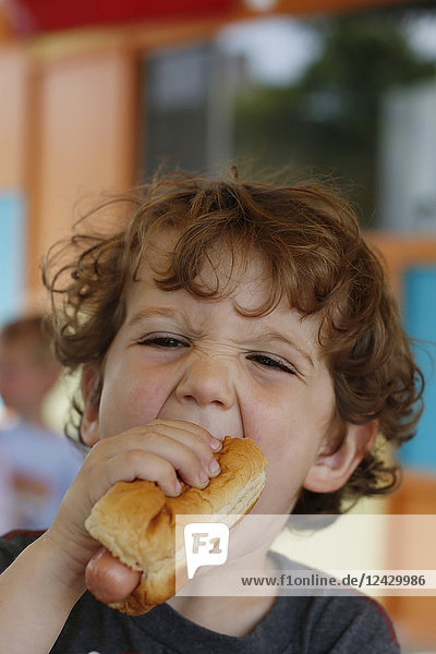 Kopfschuss eines kleinen Jungen  der einen Hotdog isst