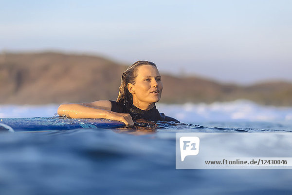Kopf- und Schulteraufnahme einer einzelnen jungen Frau beim Surfen im Meer