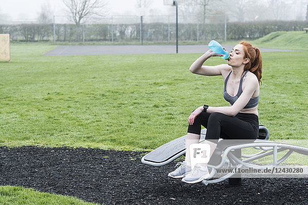 Young woman with long red hair wearing sports kit  exercising outdoors.