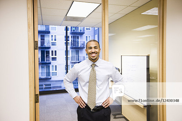 Das Porträt eines schwarzen Geschäftsmannes  der allein in seinem Büro steht.