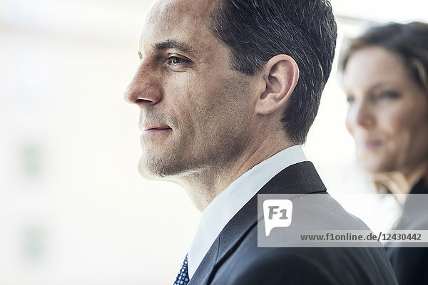 Close-up of a Caucasian businessman looking out the widow of a conference centre lobby.