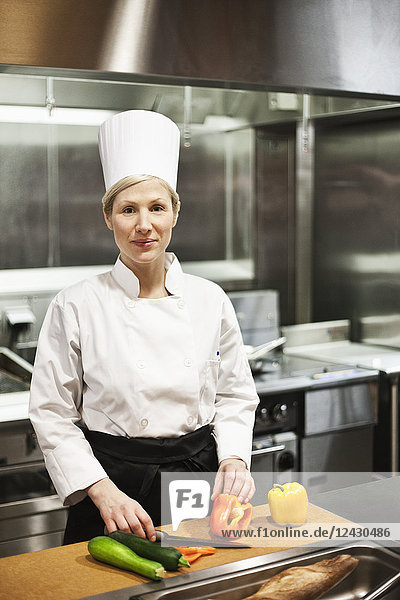 A portrait of a Caucasian female chef in a commercial kitchen.