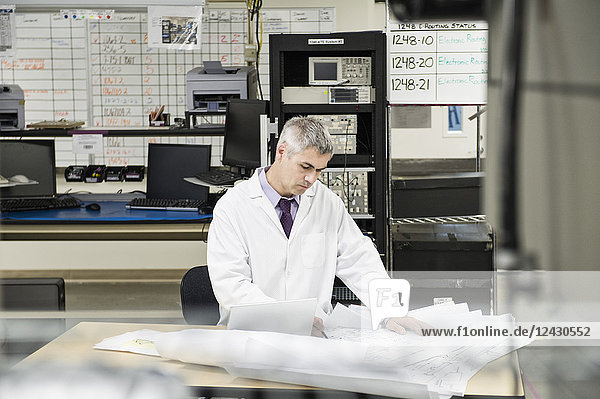 A male Caucasian technician working over a problem r in a technical research and development site.