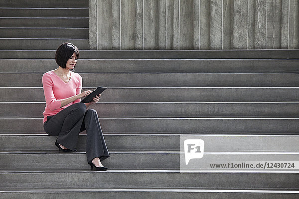 Hispanische Geschäftsfrau  die an einem Notebook-Computer arbeitet  während sie auf Stufen in einem Kongresszentrum sitzt.