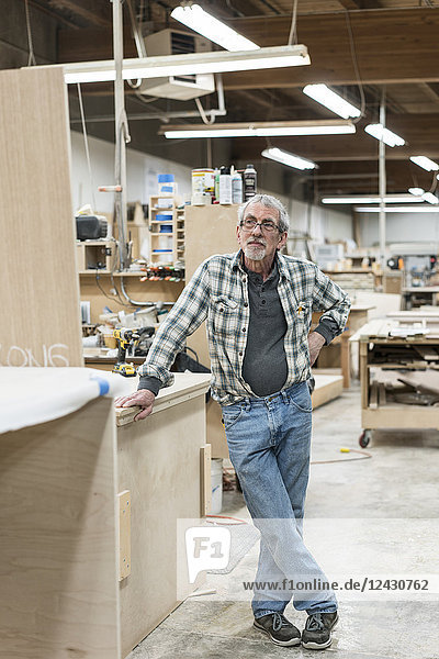 Portrait of a senior Caucasian carpenter in a large woodworking shop.