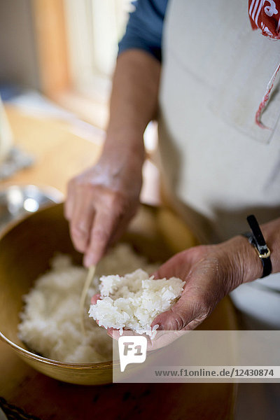 Close up of woman standing at a table in a kitchen  making sushi.