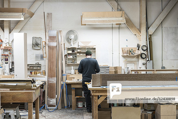 Carpenter working on a cabinet project at his work station in a furniture factory.