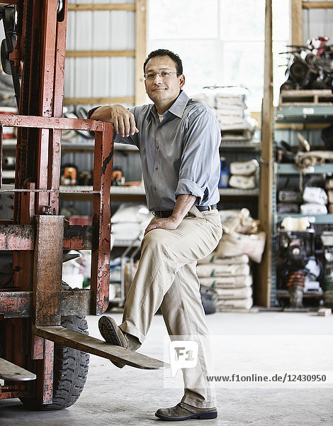 Hispanic man owner of a landscape company standing in the equipment room