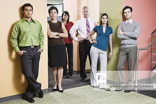 Mixed race team of workers in an office hallway.