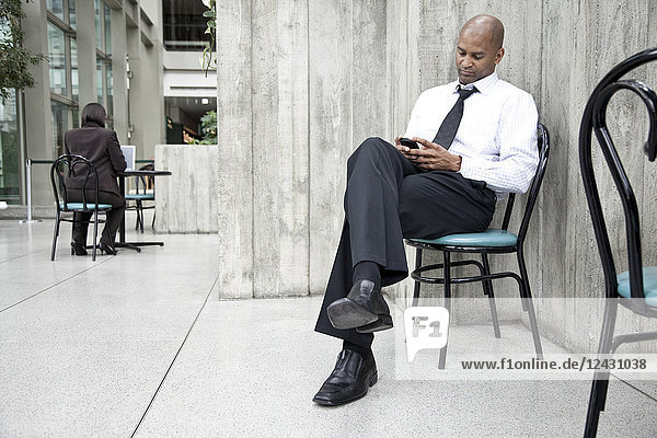 Ein schwarzer Geschäftsmann schreibt eine SMS auf seinem Handy.