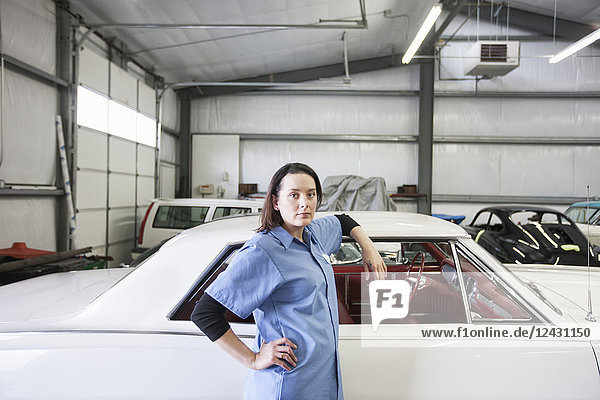 Das Porträt einer kaukasischen Mechanikerin in einer Autowerkstatt.