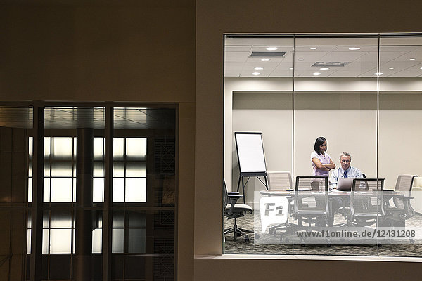 Ein großes Gebäude  Lobby  Blick in ein Büro mit Glaswänden  zwei Geschäftsleute im Gespräch.