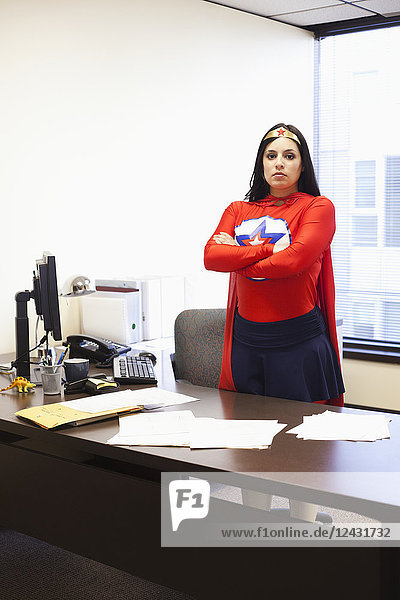 An Hispanic businesswoman office super hero at her office computer
