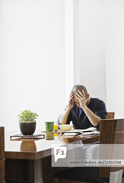 Hispanic man under stress while sitting at the dining room table in a new home.