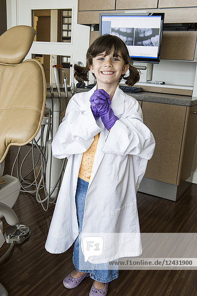 A portrait of a young Caucasian girl playing dress up in a dental office.