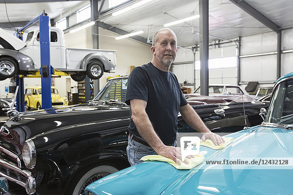 A Caucasian senior male car mechanic in his classic car repair shop.