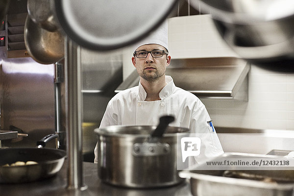 A portrait of a Caucasian male chef in a commercial kitchen.