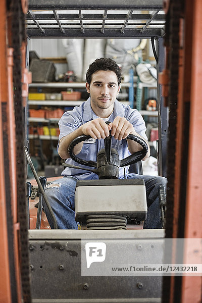 Caucasian man employee driving a forklift for a landscape company.