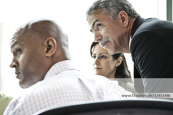 A middle eastern businessman listens to a conversation in a business meeting.