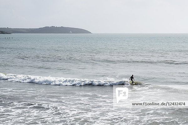 Surfer im Neoprenanzug reitet in Küstennähe auf der Meereswelle.